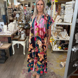 Woman in a colorful dress standing in a store with shelves and products in the background