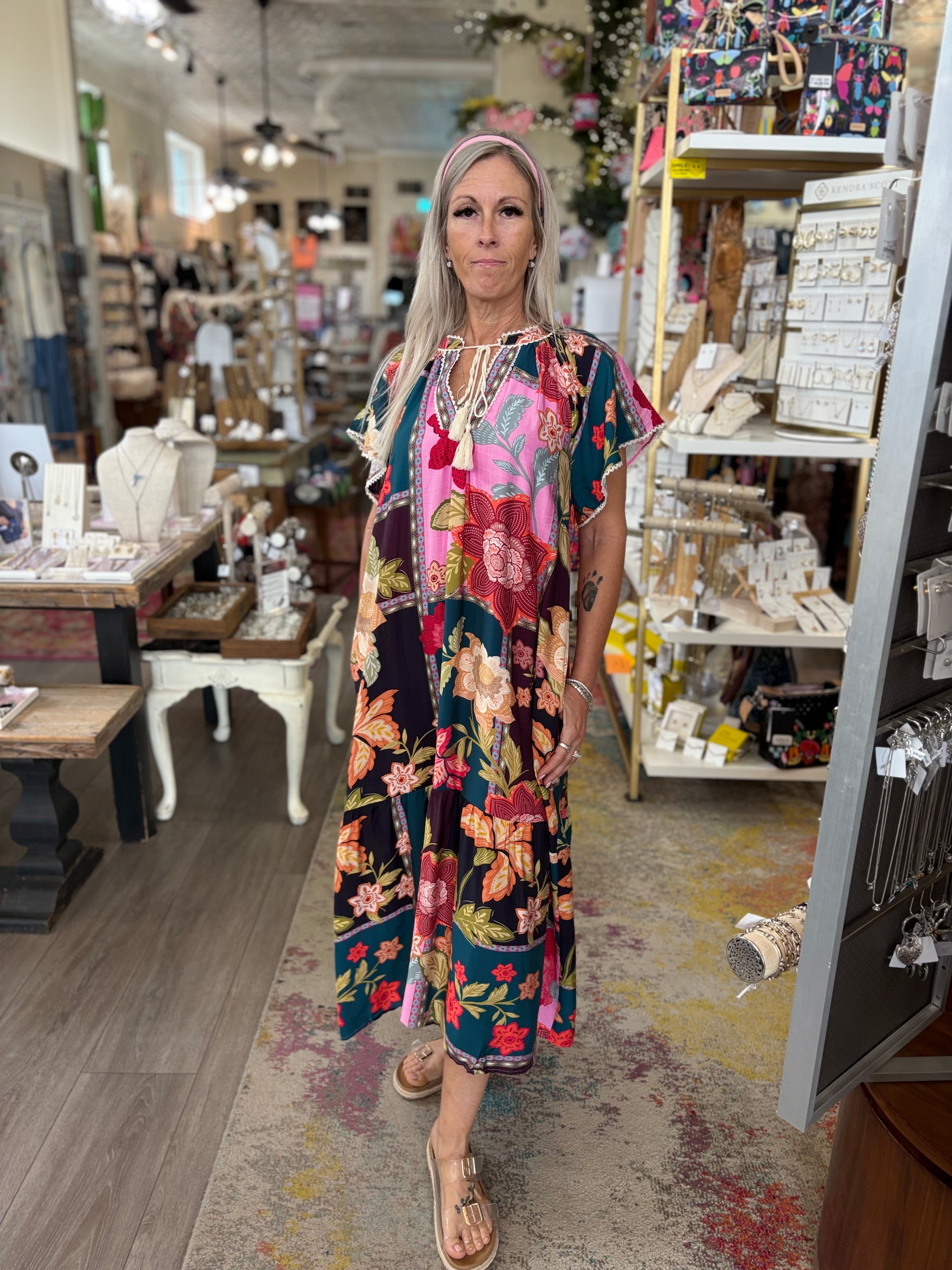 Woman in a colorful dress standing in a store with shelves and products in the background