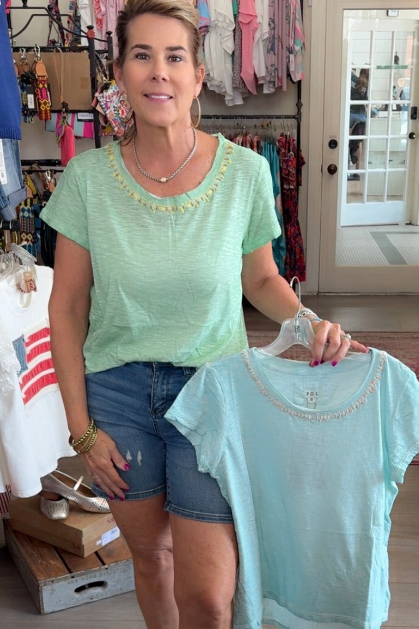 Woman holding a light blue t-shirt in a store setting