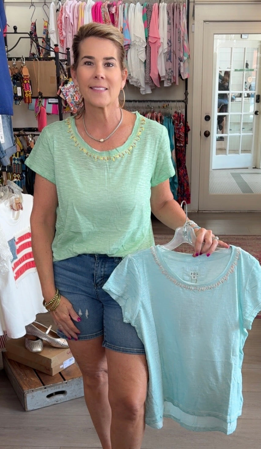 Woman holding a light blue t-shirt in a store setting