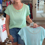 Woman holding a light blue t-shirt in a store setting