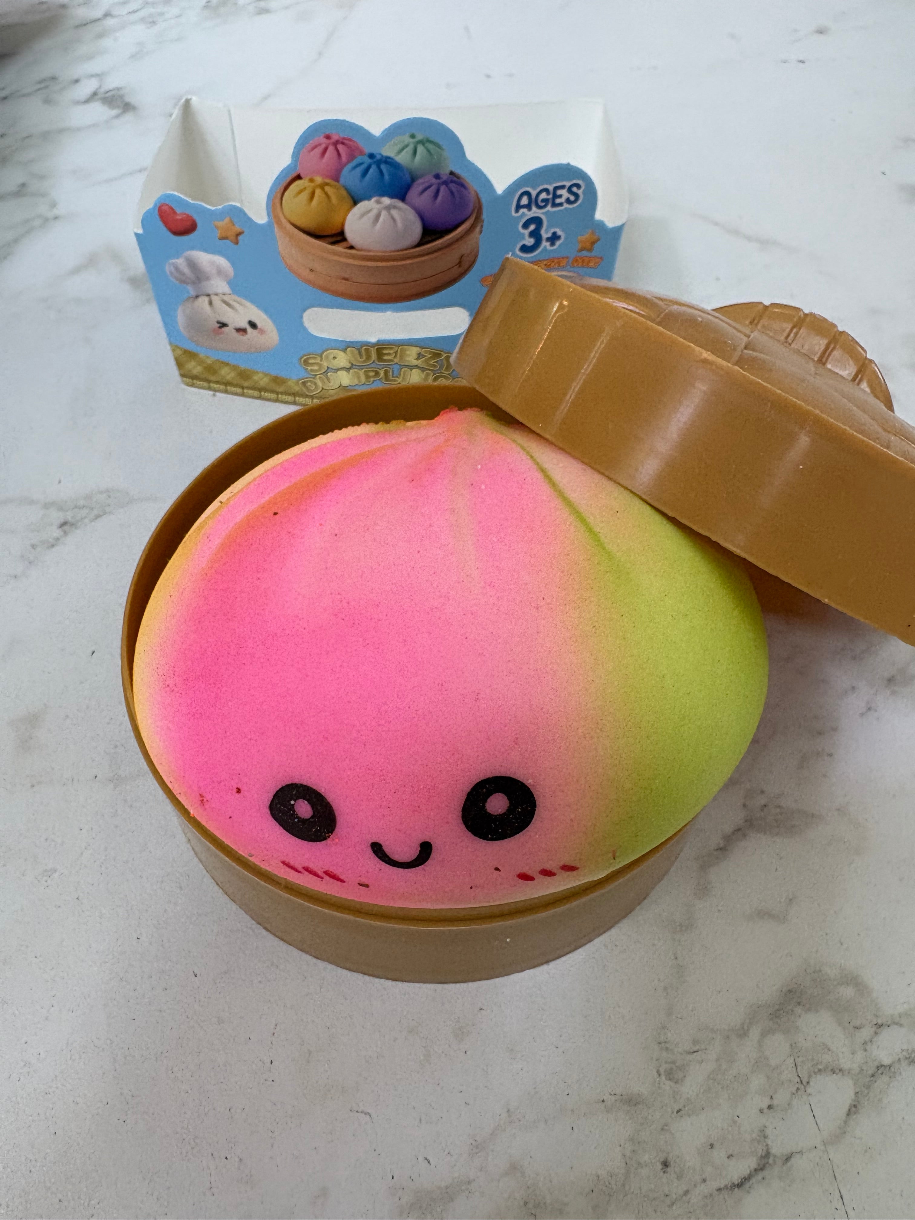 Squishy toy with a smiley face in a brown container on a marble surface