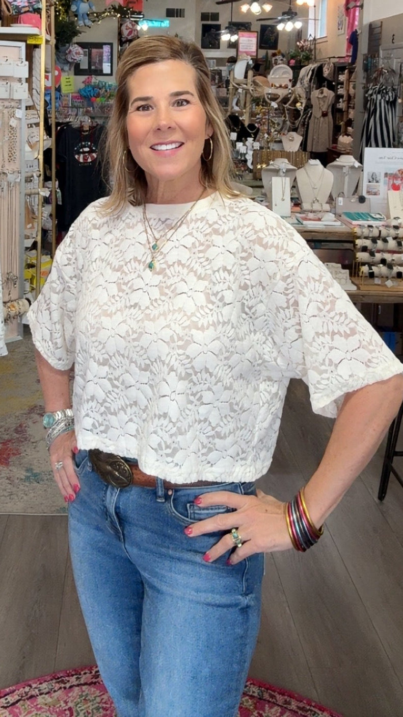 Woman standing in a store with clothing and decor items around her
