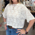 Woman standing in a store with clothing and decor items around her
