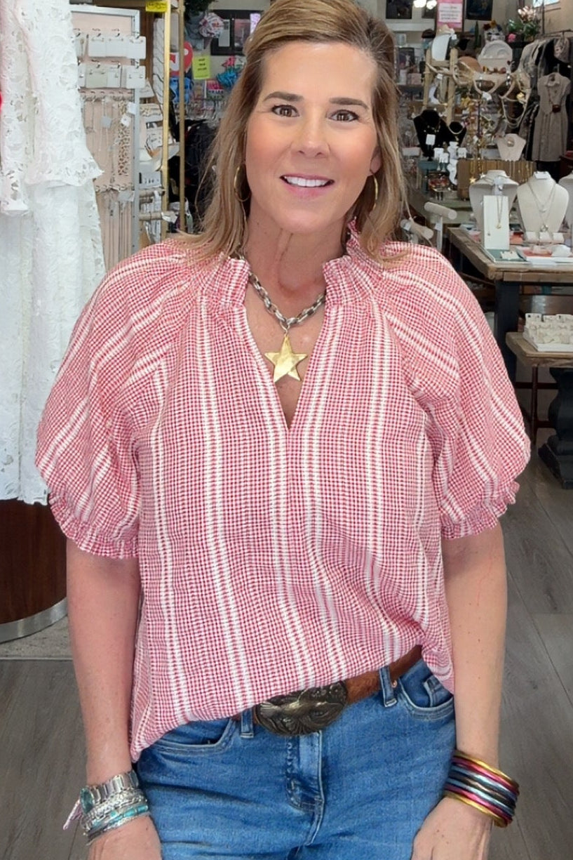 Woman in a pink striped shirt and blue jeans standing in a store.