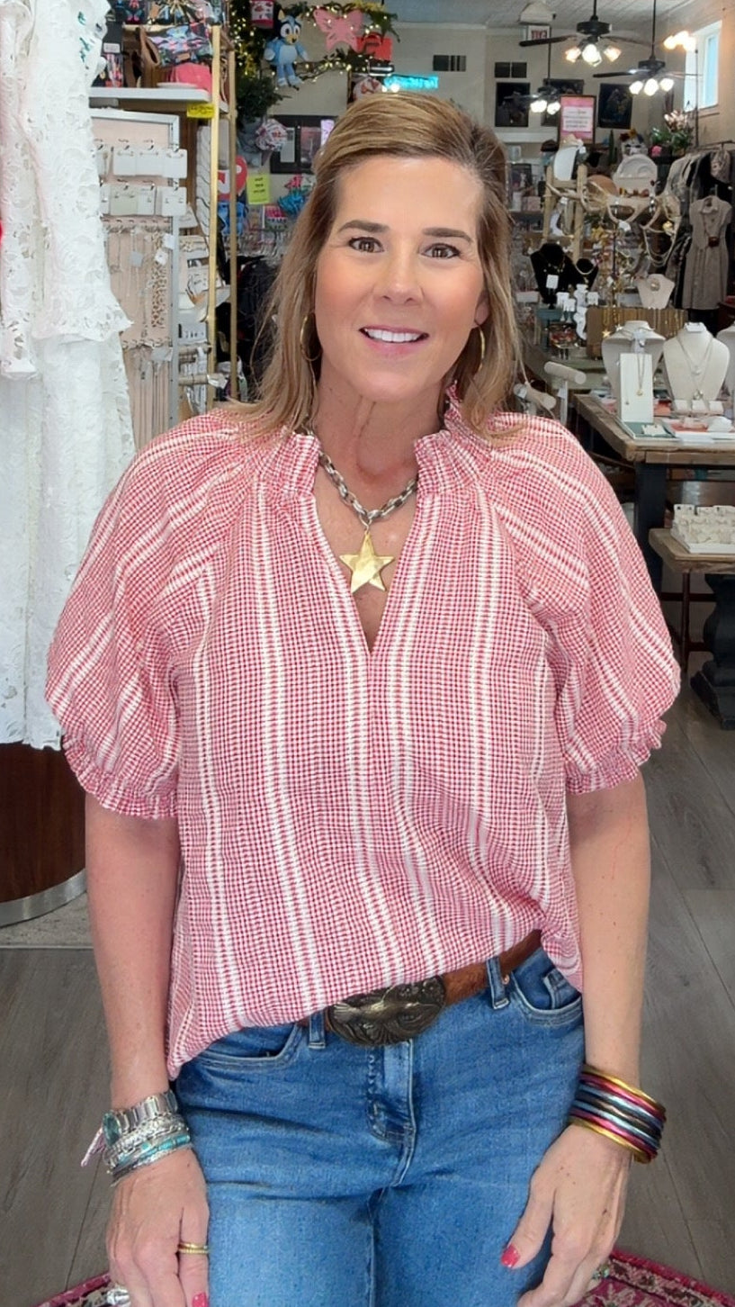 Woman in a pink striped shirt and blue jeans standing in a store.