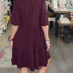 Woman in a maroon dress walking through a store with various items on display.