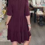 Woman in a maroon dress walking through a store with various items on display.