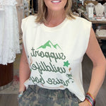 Woman standing in a store wearing a sleeveless shirt with text and graphics