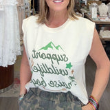 Woman standing in a store wearing a sleeveless shirt with text and graphics
