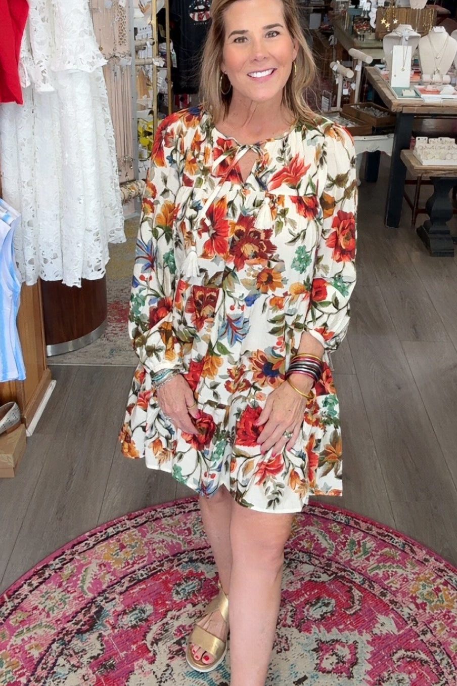 Woman in a floral dress standing in a store with various items on display.