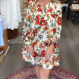 Woman in a floral dress standing in a store with various items on display.