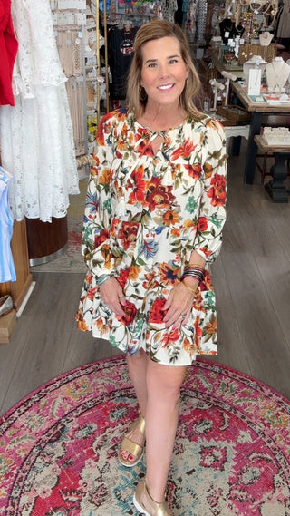 Woman in a floral dress standing in a store with various items on display.