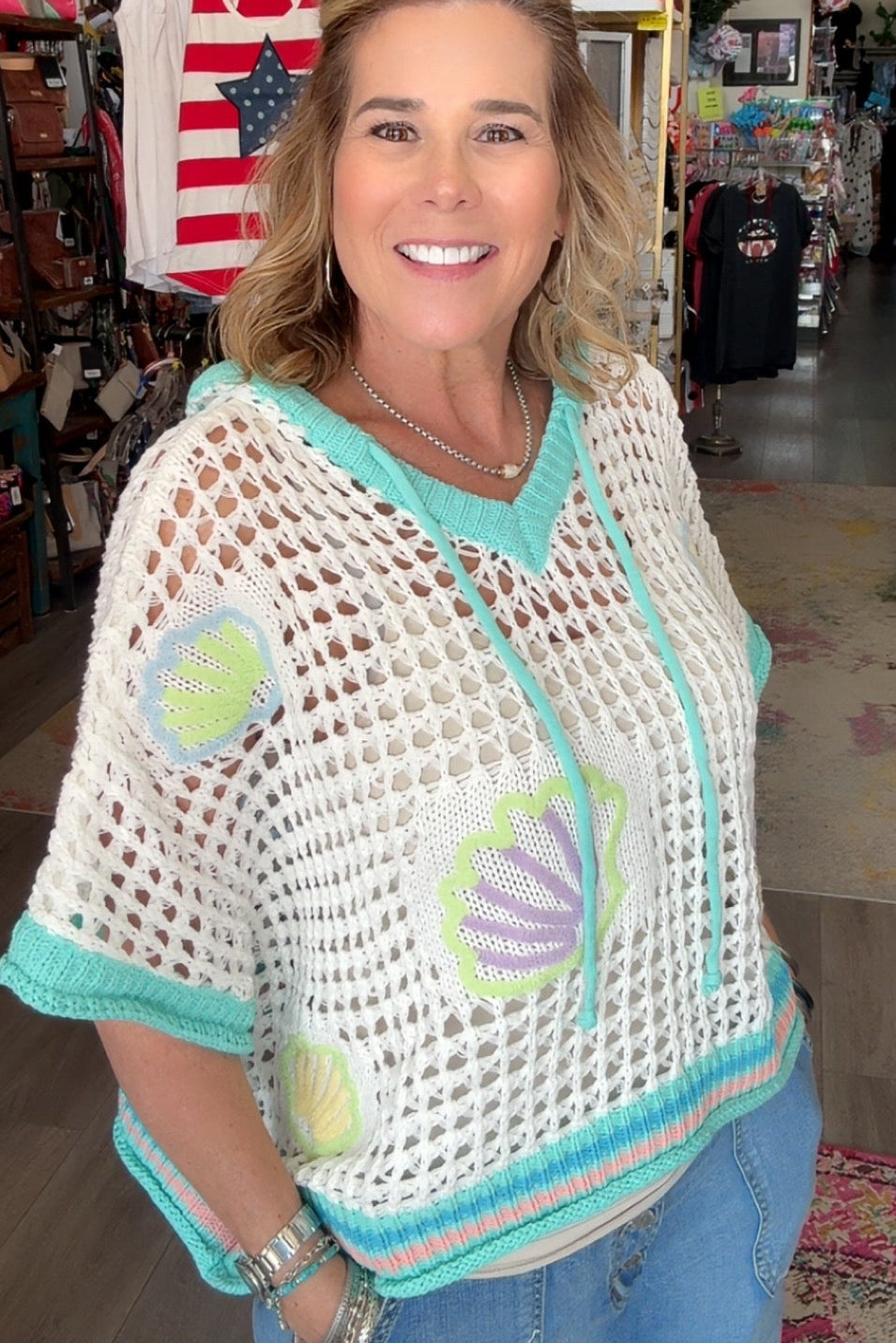 Woman wearing a crochet top with shell patterns in a store setting