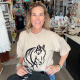 Woman holding a black t-shirt with a white horse design in a store setting