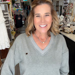 Woman in a gray sweater and blue jeans standing in a store.