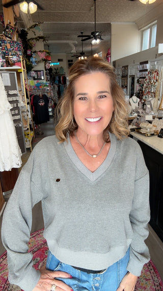 Woman in a gray sweater and blue jeans standing in a store.