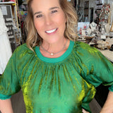 Woman wearing a green top and blue jeans in a store setting