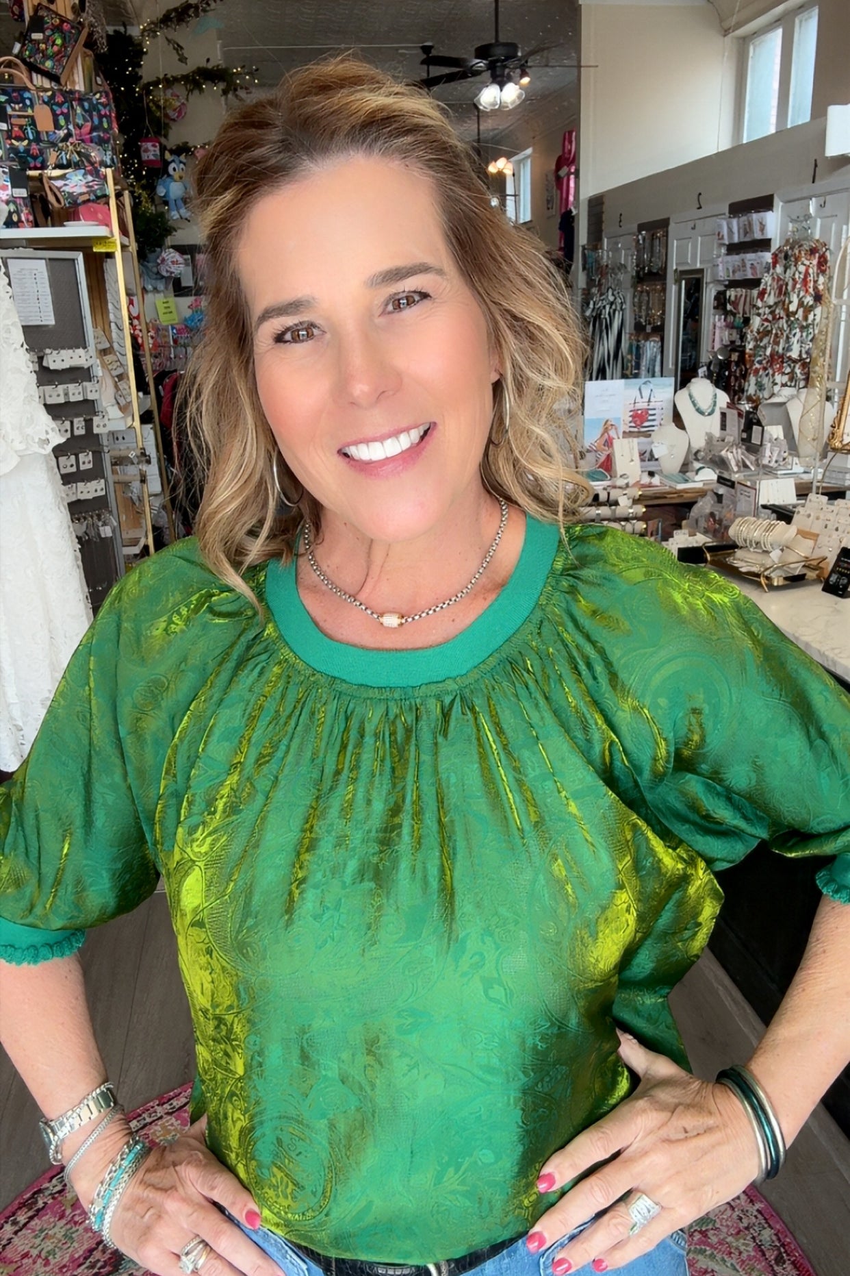 Woman wearing a green top and blue jeans in a store setting
