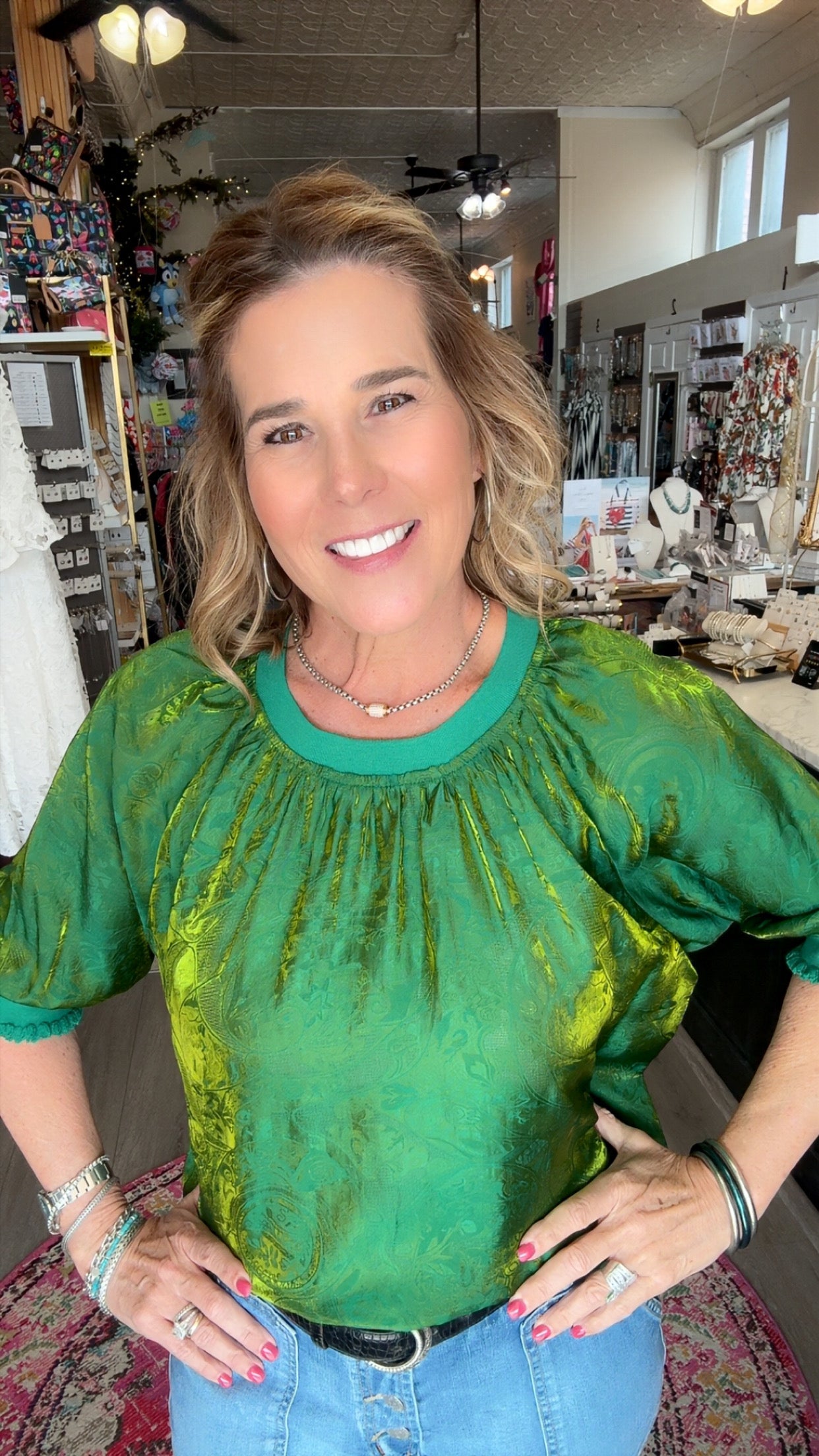 Woman wearing a green top and blue jeans in a store setting