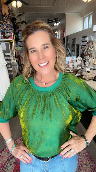 Woman wearing a green top and blue jeans in a store setting