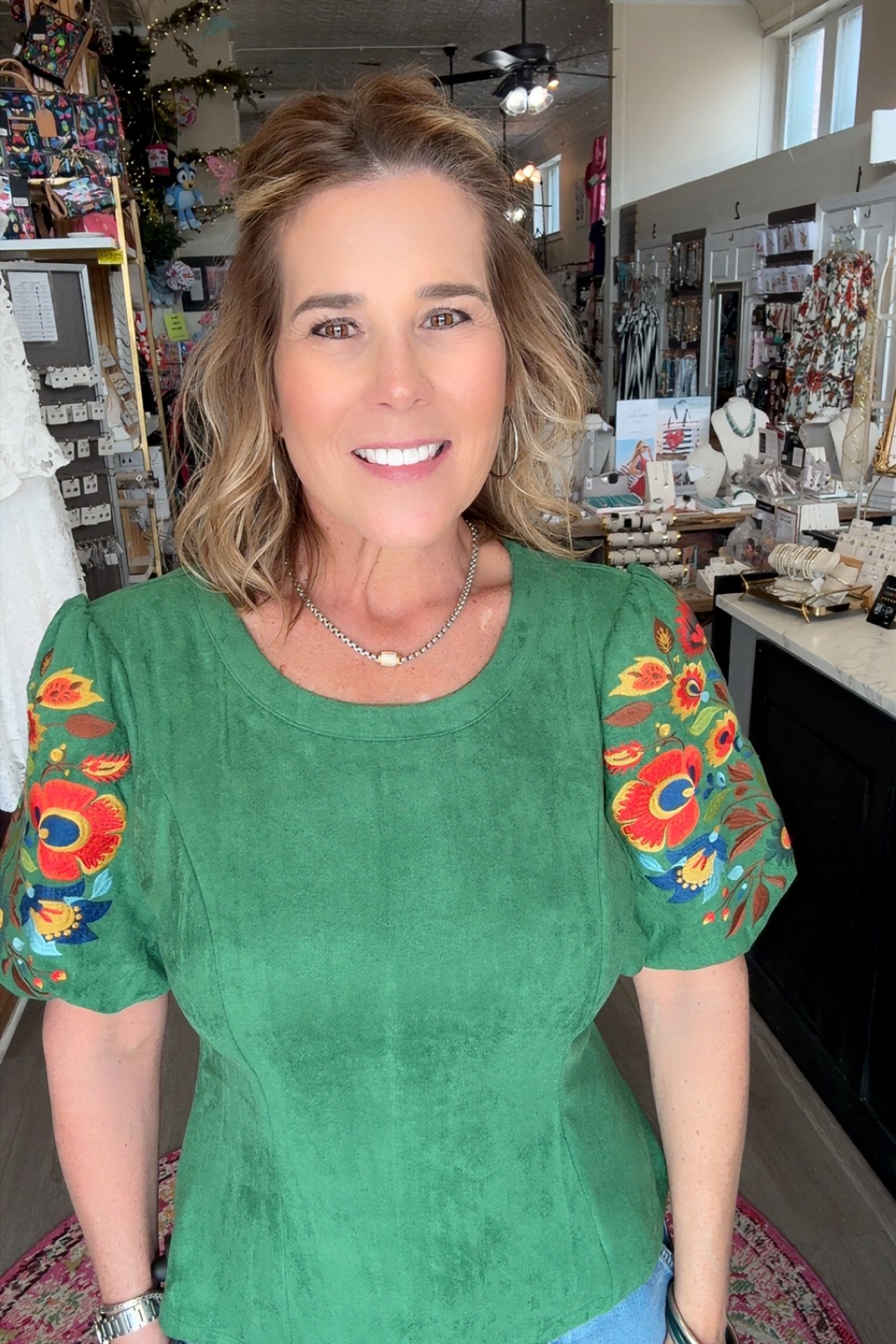 Woman wearing a green top with colorful sleeves in an indoor setting