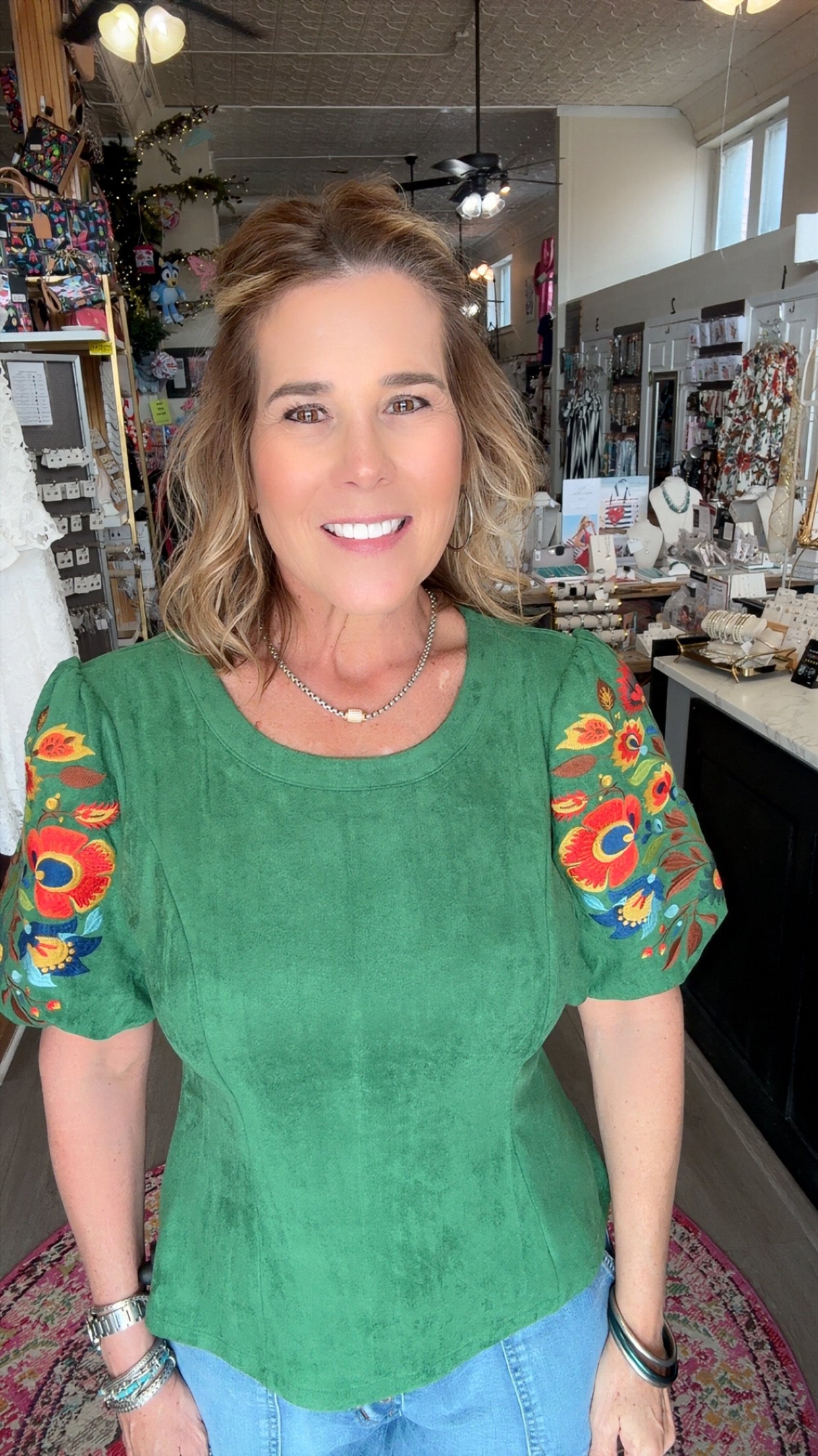 Woman wearing a green top with colorful sleeves in an indoor setting