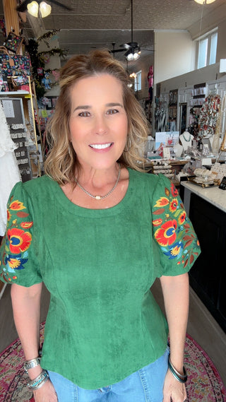 Woman wearing a green top with colorful sleeves in an indoor setting