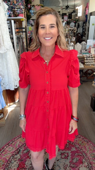 Woman in a red dress standing in a store with various items in the background