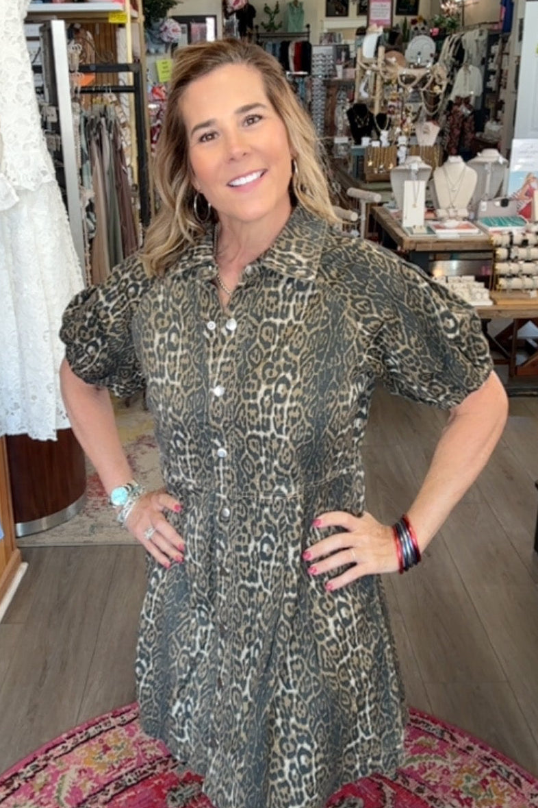 Woman in a patterned dress standing in a store with various items on shelves.
