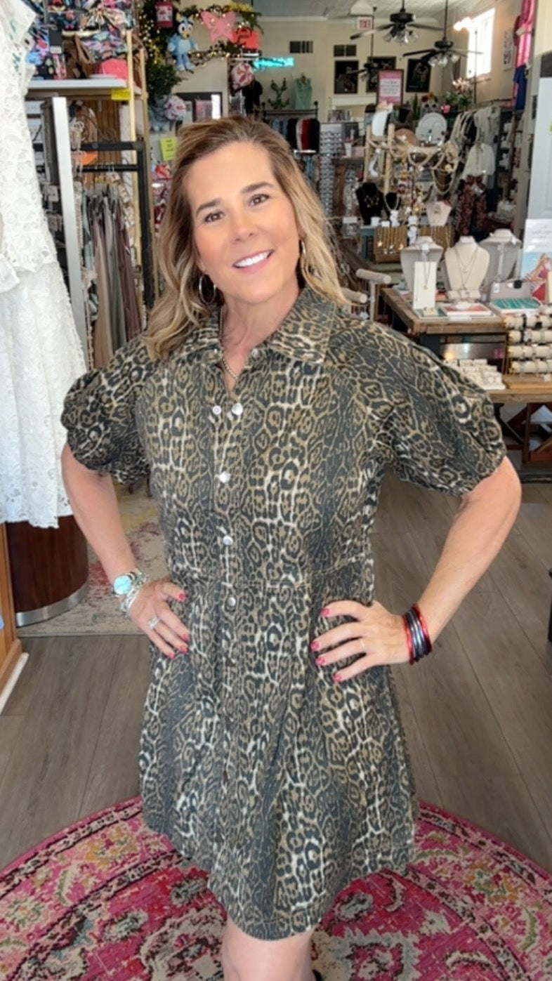 Woman in a patterned dress standing in a store with various items on shelves.