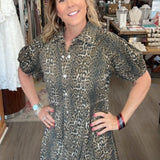 Woman in a patterned dress standing in a store with various items on shelves.