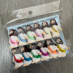 A clear plastic bag containing multiple small plush toy figures arranged in two columns on a gray wood-textured surface. The packaging card reads 'YOU'RE NOT ENOUGH MOVEMENT'.