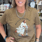 A woman wearing a brown leopard-print graphic t-shirt with a scooter illustration and the text 'EVERY BIRD WORTH A FEELING WRONG' paired with blue jeans, standing inside a retail store.