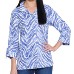 Woman wearing a blue and white patterned blouse with rolled-up sleeves on a white background