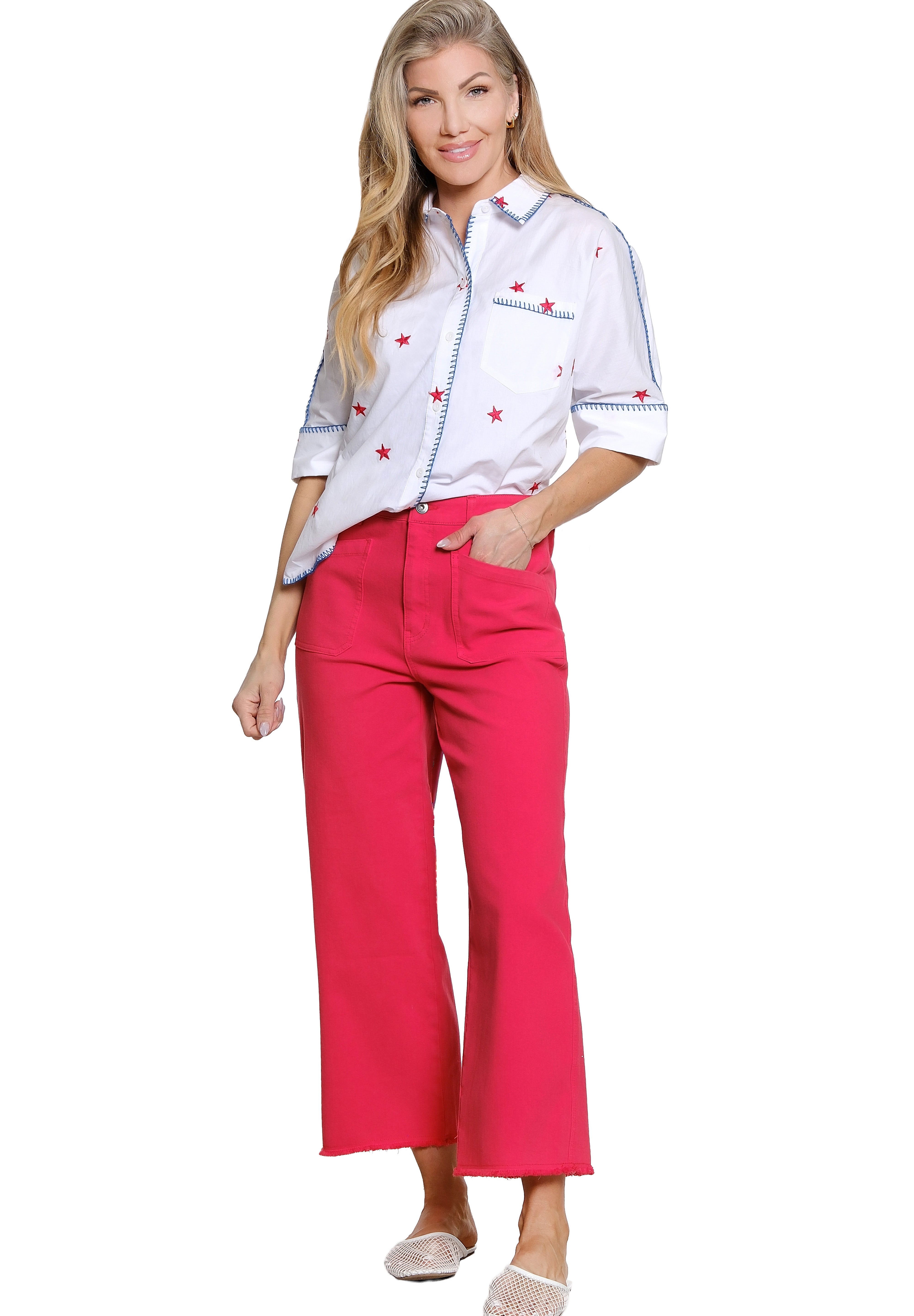 Woman wearing a white shirt with red patterns and pink pants on a white background