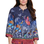 Woman wearing a colorful butterfly-patterned shirt on a white background