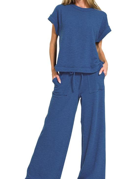 Woman wearing a blue outfit with a top and wide-leg pants on a white background