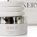 Skincare product jar labeled 'SHINERY' with a blurred magazine in the background