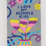 A towel with a colorful floral and ass-related design, text reading 'I LOVE MY ASSHOLE KIDS' on it.