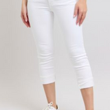 Person wearing white capri pants on a plain background