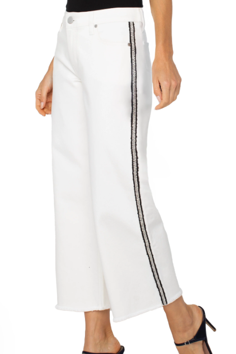 White pants with black side stripes worn by a person on a white background