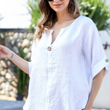 Woman wearing a white blouse and sunglasses by a pool