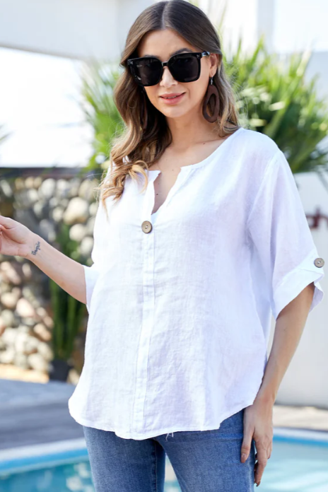 Woman wearing a white blouse and sunglasses by a pool