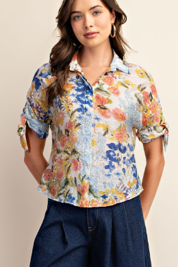 Woman wearing a colorful floral blouse with a neutral background