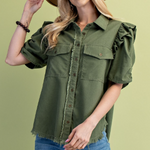 Woman wearing an olive green shirt with ruffled sleeves on a light green background