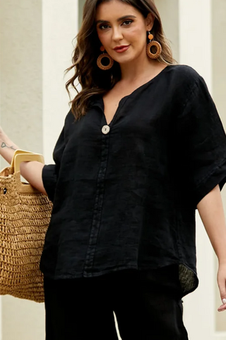 Woman in a black outfit holding a straw bag in an outdoor setting
