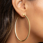 Gold hoop earring worn by a person with dark hair.