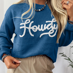 Person wearing a blue sweater with 'Howdy' text, standing against a white background.