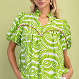 Woman wearing a green and white patterned blouse against a light green background